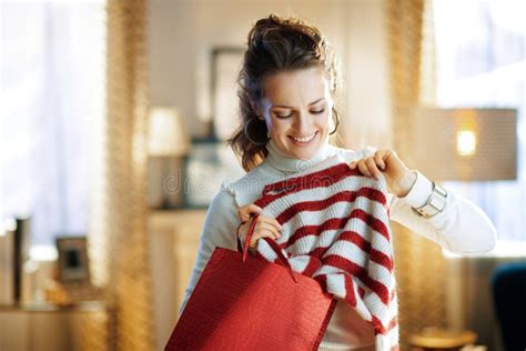 Smiling Woman With Red Shopping Bag Checking Purchased Sweater Stock