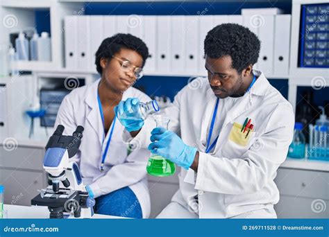 African American Man And Woman Scientists Measuring Liquid At