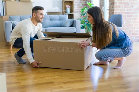 Beautiful Young Couple Moving To A New Home Holding Big Cardboard Box