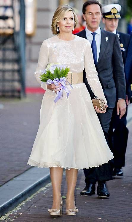 A Woman In A White Dress Walking Down The Street With A Man In Suit And Tie