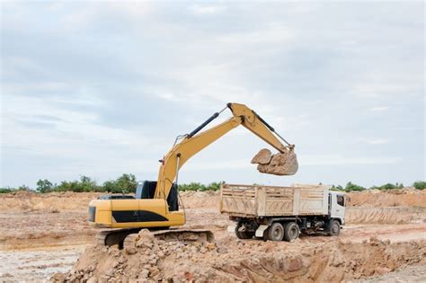 Premium Photo Yellow Excavator Machine Loading Soil Into A Dump Truck