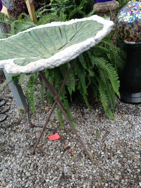 A Green Leaf Shaped Table Sitting On Top Of A Gravel Ground Next To