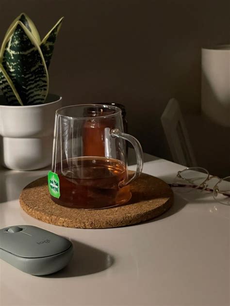 A Cup Of Tea Sitting On Top Of A Coaster Next To A Computer Mouse