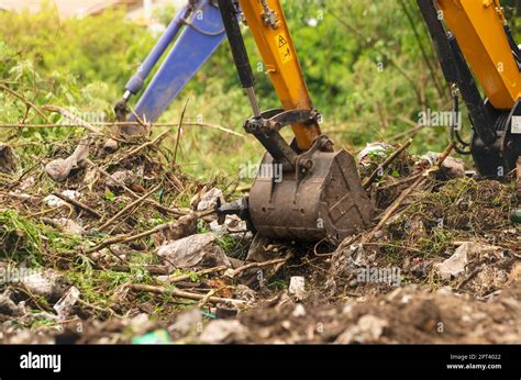 Backhoe digging soil at construction site. Bucket of backhoe digging soil. Clearing and grubbing ...