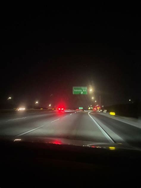 An Image Of A Highway At Night With Traffic Lights And Street Signs In