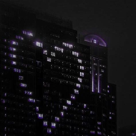 The Building Is Lit Up With Purple Lights In The Dark Night Sky And It