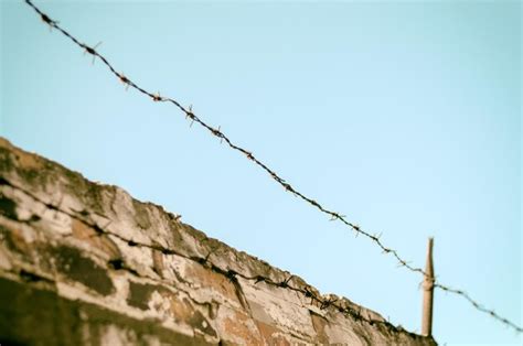 Premium Photo Low Angle View Of Barbed Wire Over Wall Against Clear Sky