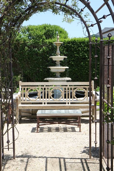 A Wooden Bench Sitting Under An Archway Next To A Fountain