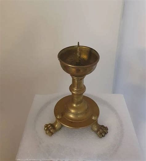 An Antique Brass Candle Holder On A White Towel