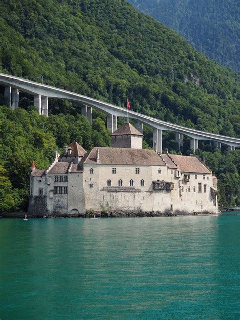 An Old Castle Sits On The Edge Of A Large Body Of Water With A Bridge