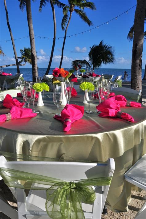 The Table Is Set With Pink And Green Flowers In Vases Napkins And