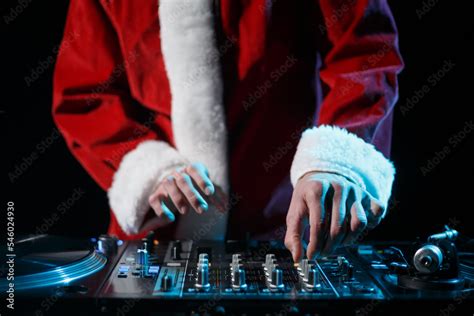 Christmas DJ in Santa Claus costume playing music in night club. Disc jockey wearing traditinal ...