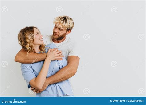 Young Cheerful Couple Hugging While Standing Isolated Over White Wall