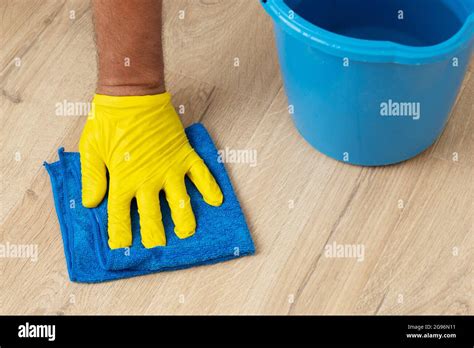 Hand Wearing An Yellow Rubber Glove Washing A Laminate Flooring With A