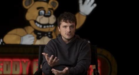 A Man Sitting In A Chair With His Hands Up To The Side And A Teddy Bear