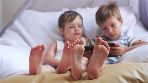 Two Cute Boys Taking a Rest at Daytime. Focus on Boys` Feet. Stock ...