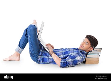 Happy Indian Man Lying On Floor Using A Laptop Pc Looking At Camera