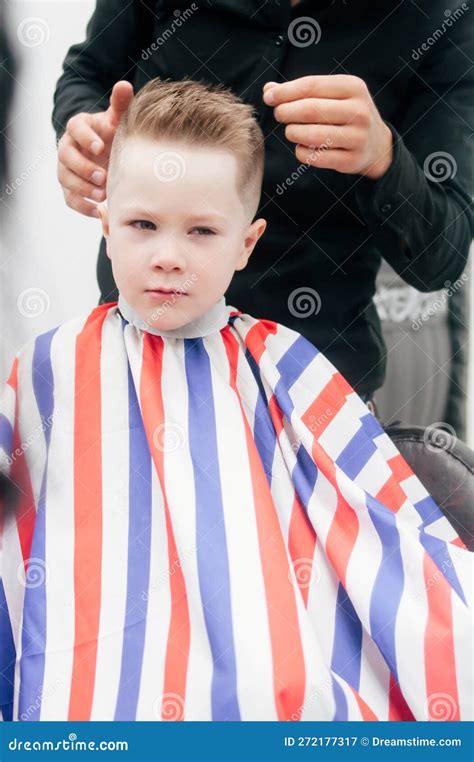 The Boy Kid Is Getting A Haircut In A Barbershop Hair Stylist Indoor