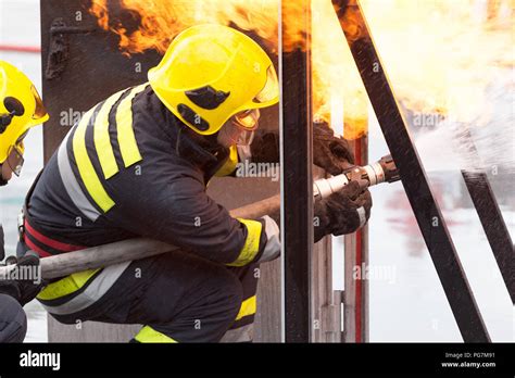 Los bomberos en acción extinguir el fuego con manguera contra