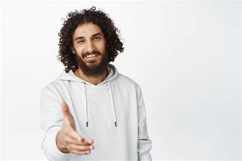 Um jovem sorridente e bonito estende a mão para um aperto de mão