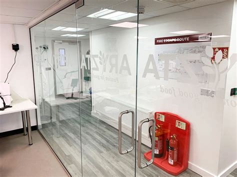 An Office With Glass Walls And Red Phone Booth