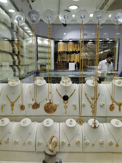 gold necklaces are displayed in a store window as a man stands behind the counter