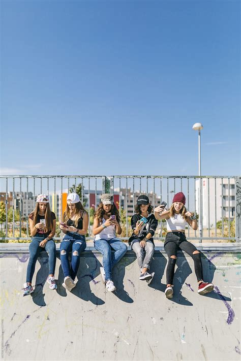 "Group Of Young Girls Using Their Mobile Phones In The Street" by