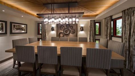 A Dining Room Table And Chairs With Lights Hanging From The Ceiling