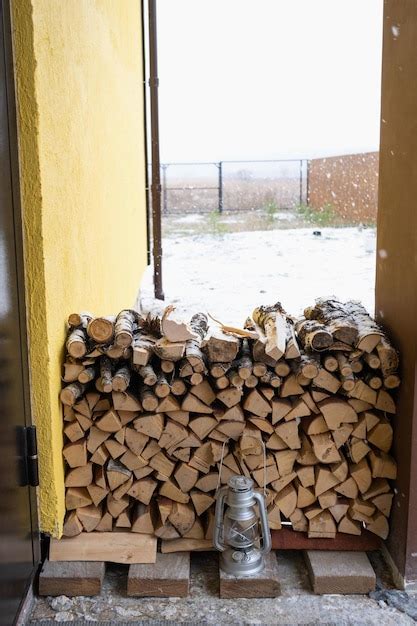 A lenha no alpendre nevado da casa é colhida para o inverno aquecimento