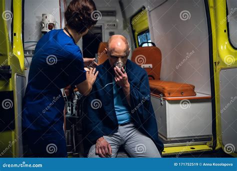 Corpsman Puts Oxygen Mask On Woman Liyng On Stretcher In The Ambulance