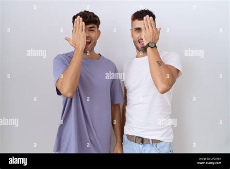 Homosexual Gay Couple Standing Over White Background Covering One Eye With Hand Confident Smile