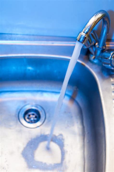 A Stream Of Clean Water Flows Into The Stainless Steel Sink In Blue