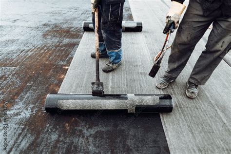 Foto De Construction Workers Roofers Installing Rolls Of Bituminous