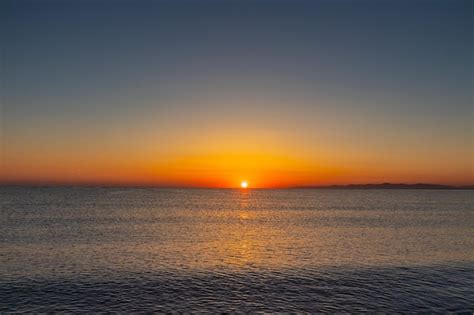 Premium Photo | Sunset over the ocean with mountains in the background