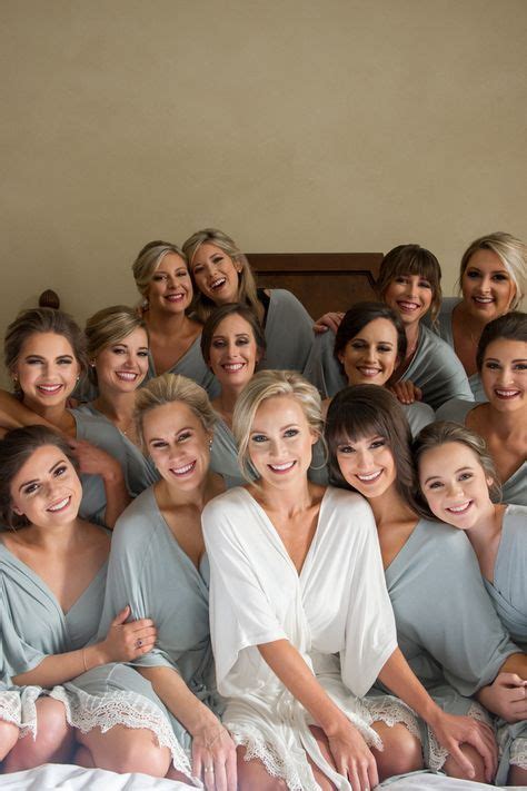 A Group Of Bridesmaids Pose For A Photo In Their Robes On The Bed