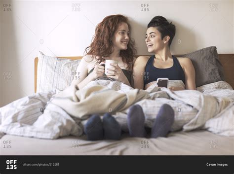 Happy Lesbian Couple Looking At Each Other While Sitting On Bed Stock Photo OFFSET