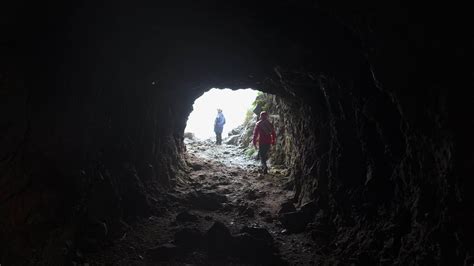 View from cave to tourists. Clip. Rear view of man coming out of cave