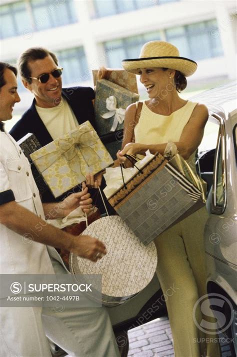 Personal valet carrying a mid adult woman's shopping bags - SuperStock