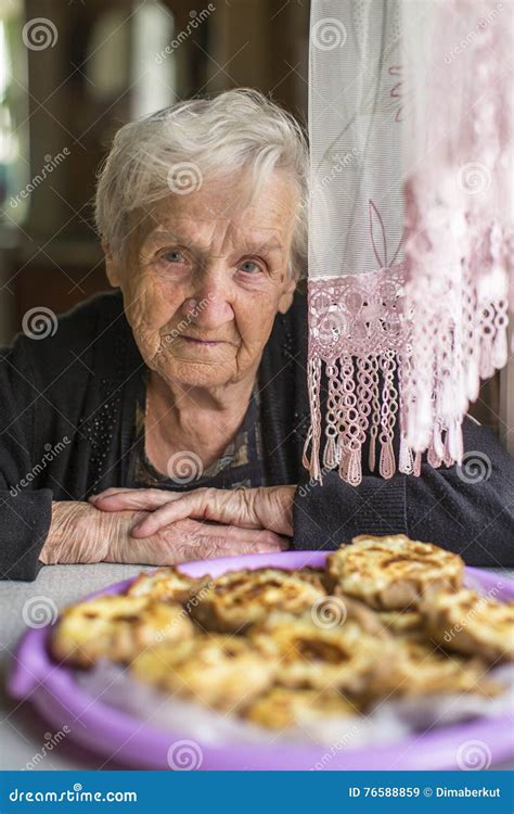 Uma Mulher Idosa Que Senta Se Em Uma Tabela Um Pastel Careliano