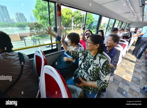 Elderly Chinese people take a sightseeing bus to travel around tourist attractions in Shanghai ...