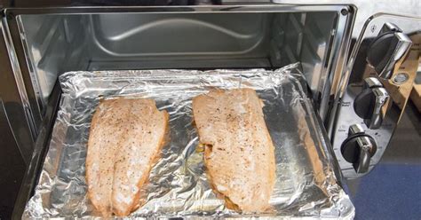 Two Fish Fillets Sitting On Tin Foil In An Oven