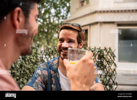 A Gay Couple Shares A Joyful Moment Sipping Drinks And Engaging In A Light Hearted Conversation