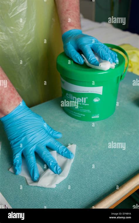 A hospital worker cleaning surfaces around a bed on a hospital ward ...