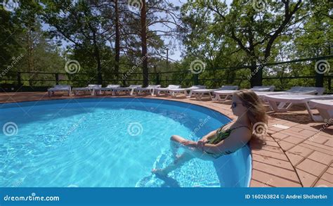 Sexual Blonde Woman Is Standing In Swimming Pool Whirling And Flirting With Camera In Sunny Day