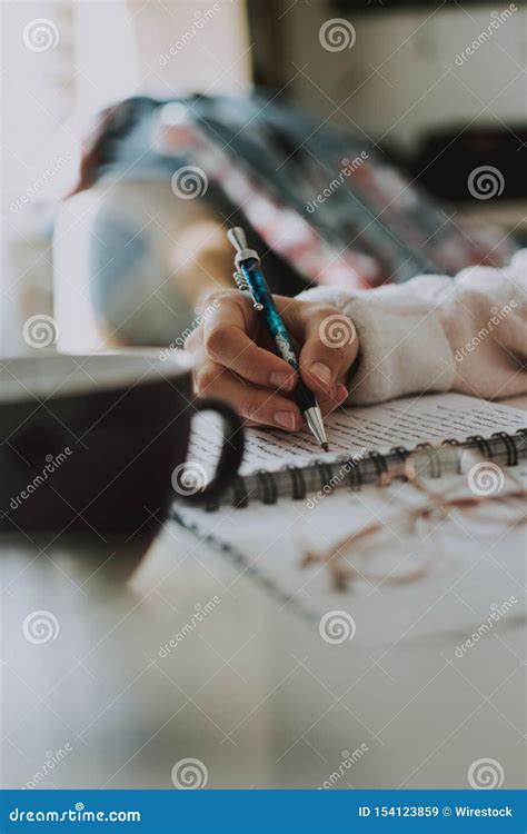 Vertical Shot Of A Female Writing Something In Her Notebook With A Pen