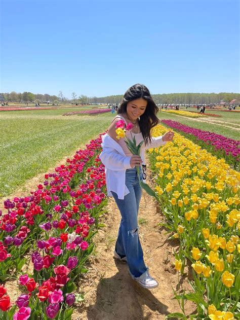 A Woman Standing In The Middle Of A Field With Lots Of Tulips And Other