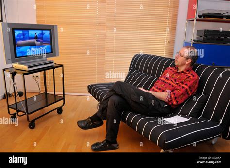 Man sitting on couch watching TV Stock Photo - Alamy