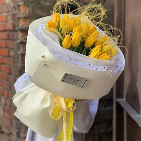 A Bouquet Of Yellow Tulips Tied To A White Bag On The Side Of A Building