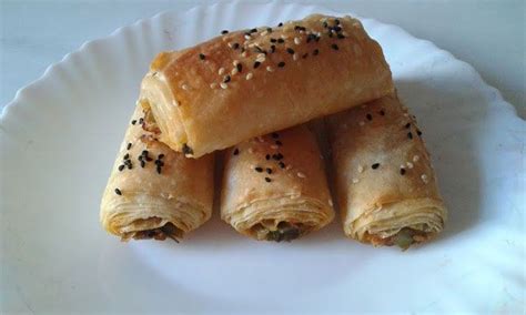 Three Pieces Of Bread Wrapped In Sesame Seeds On A White Plate