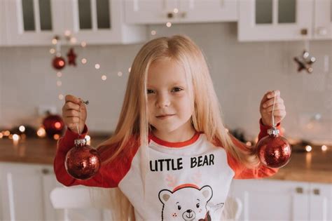 Una niña rubia con pijama rojo de navidad está sentada en la cocina y